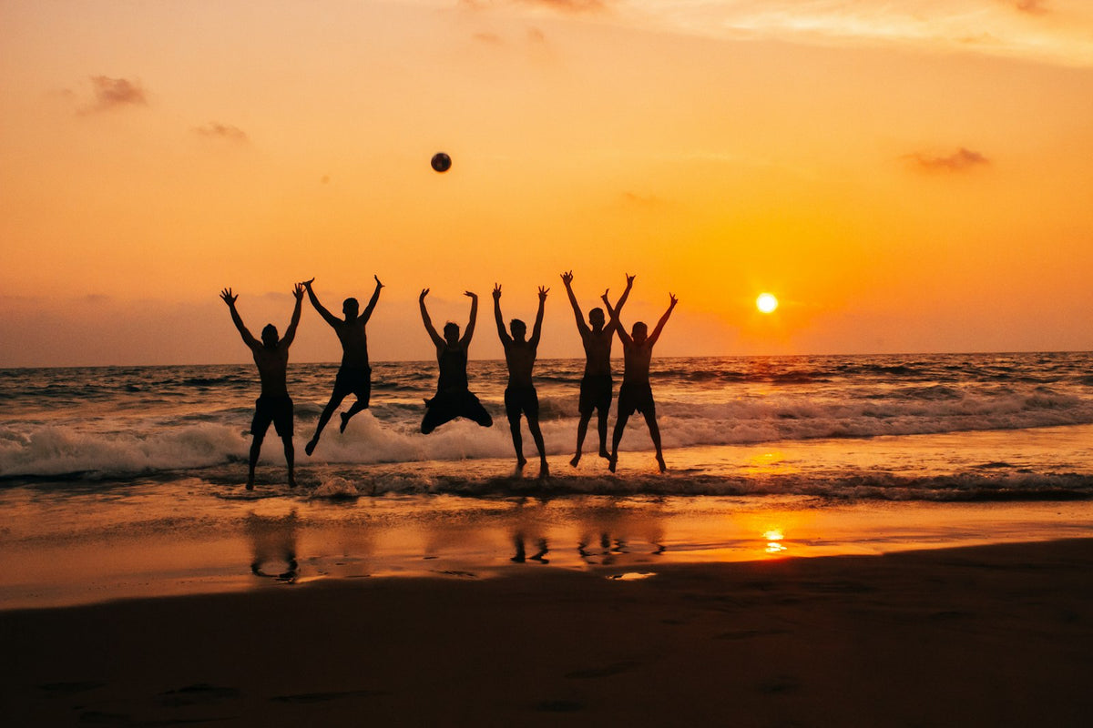 A group of friends jumping on the beach at sunset