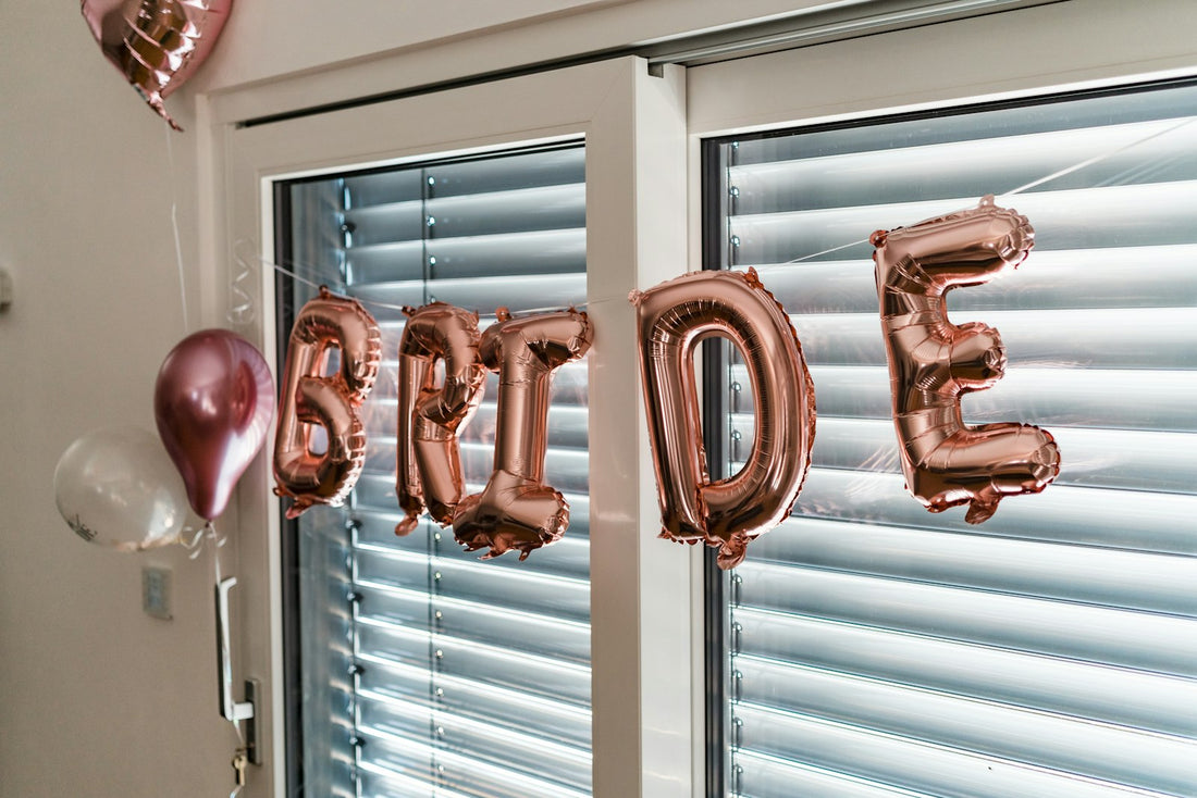 Rose gold BRIDE letter balloons hanging in a window for a bachelorette party