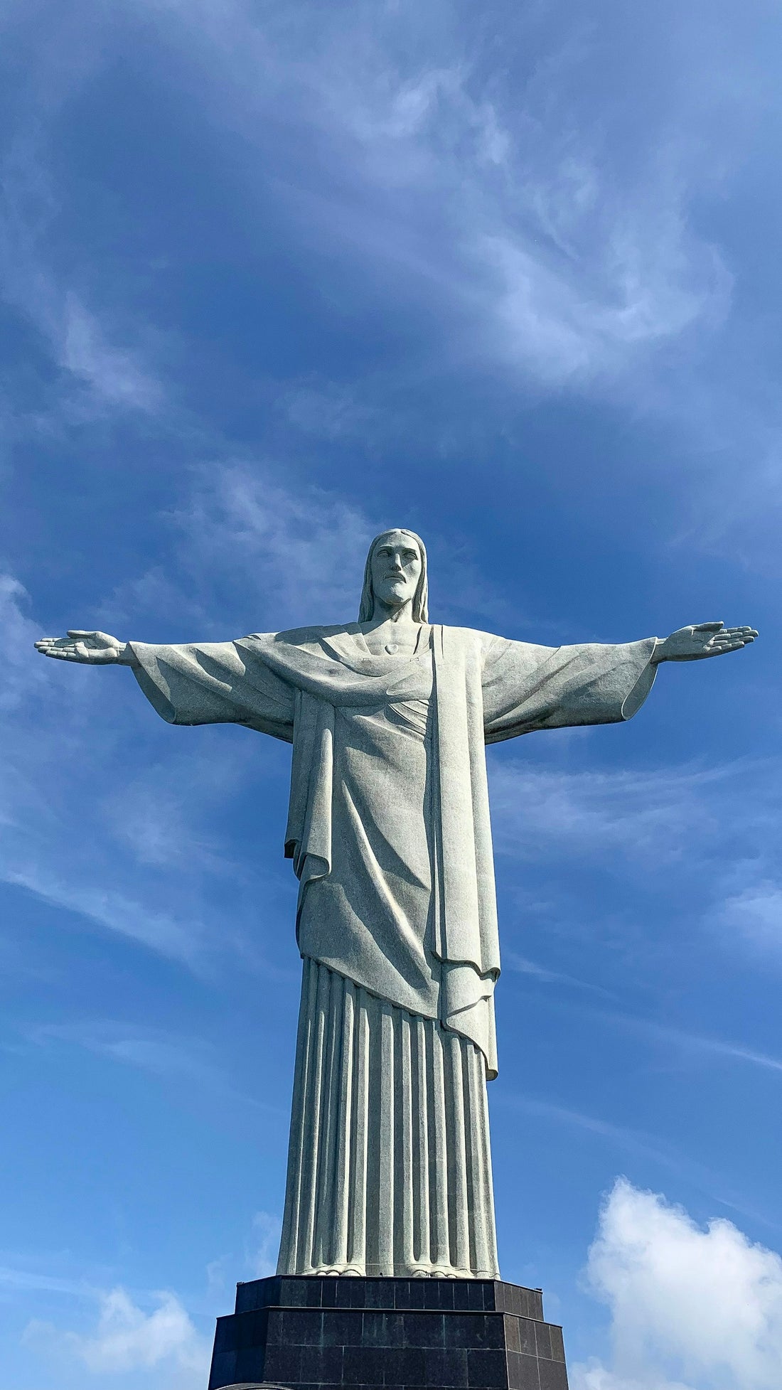 Christ the Redeemer statue with arms outstretched against a bright blue sky in Rio de Janeiro