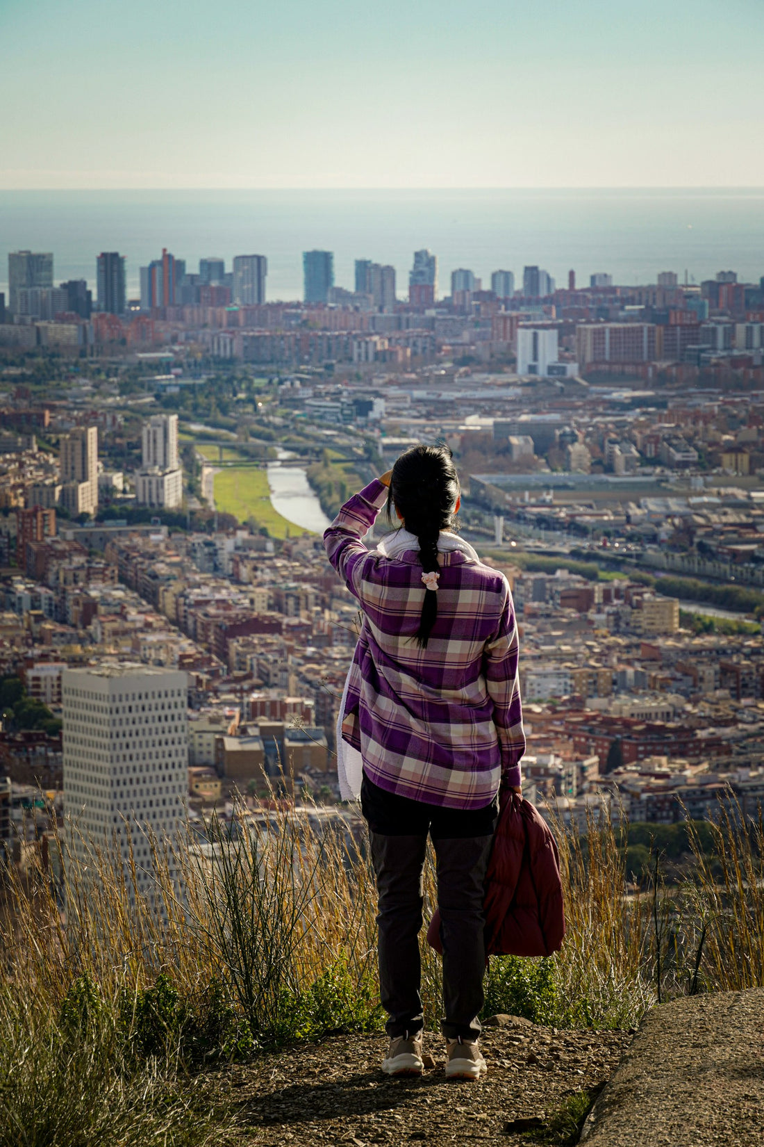 A woman traveling alone, looking out over a city from a hilltop